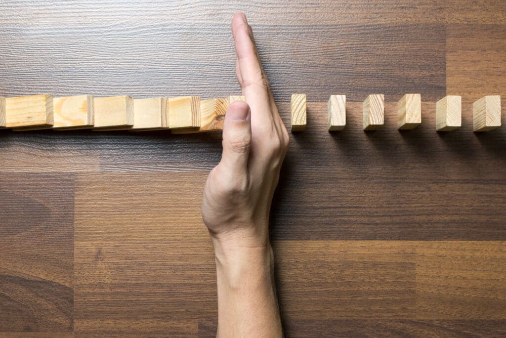 hand stopping the domino effect