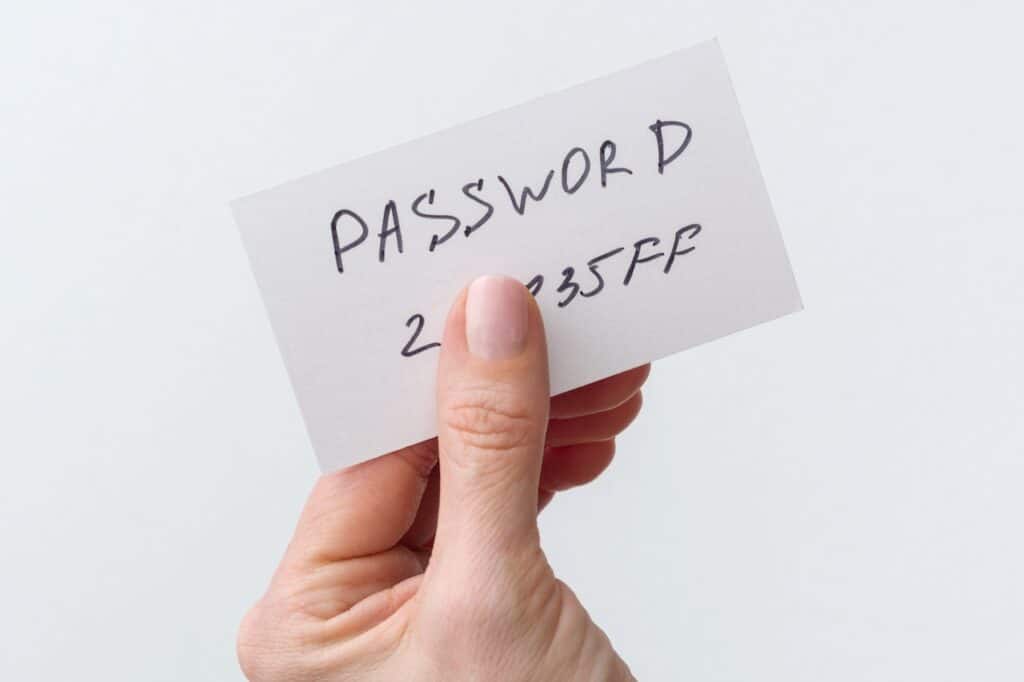 Person holding up a piece of paper that has the password of account written on it