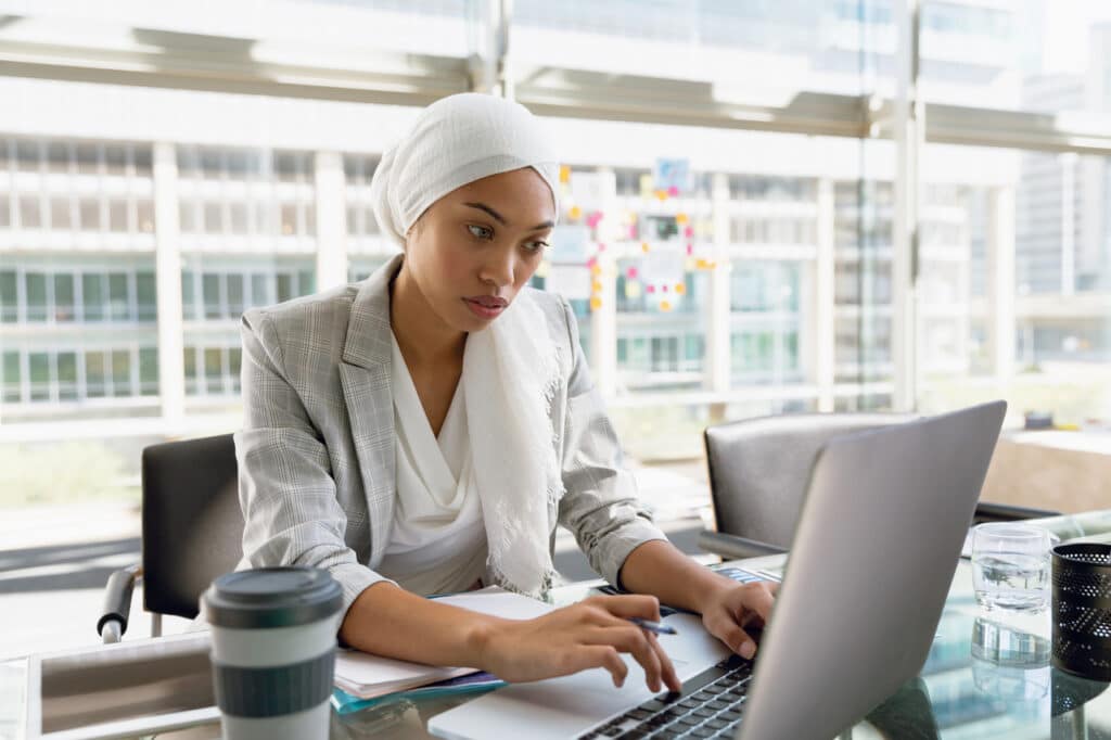Woman in hijab performing software update on laptop at desk