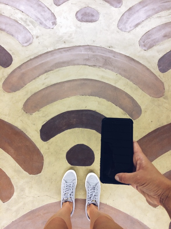 Hand holds a phone over painted wifi pattern on the floor